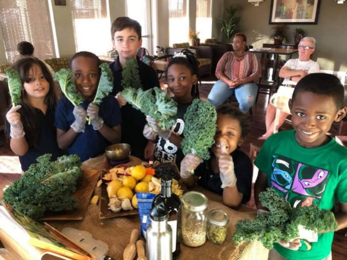 Children holding kale bunches at table